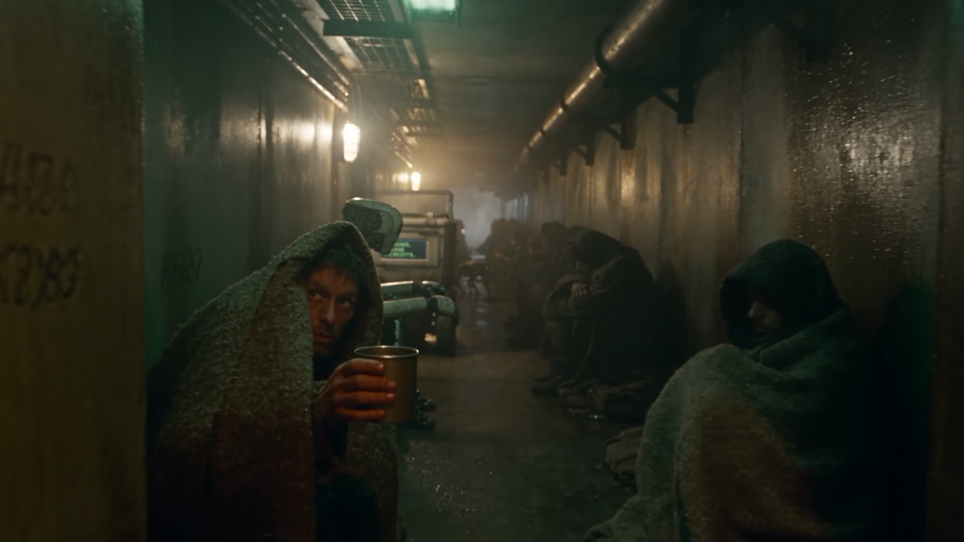 Survivors wrapped in blankets along a wet tunnel, lit by failing lamps